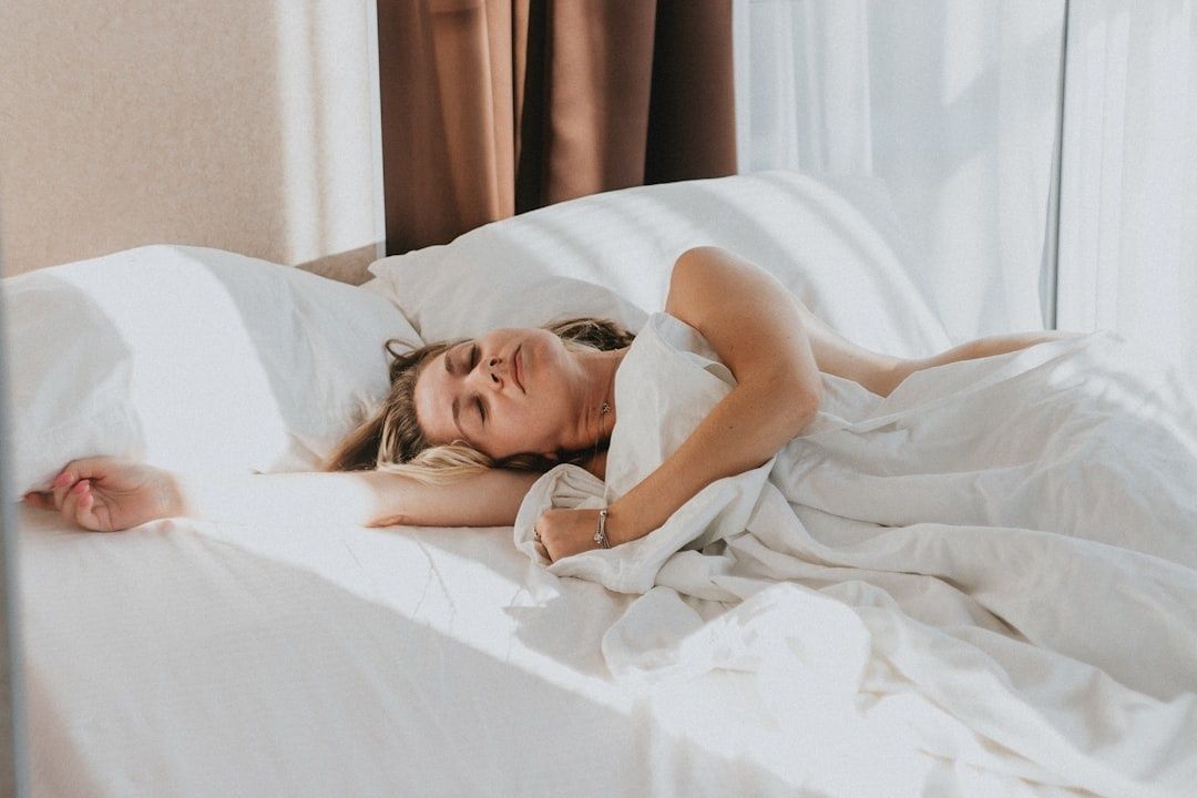 Femme endormie dans un lit baigné de lumière naturelle